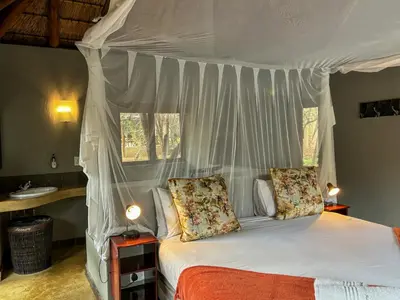 a bedroom with a white canopy bed with two pillows at Hoedspruit Raptors Lodge N16 in Hoedspruit