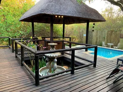 a large umbrella on a deck next to a pool at Hoedspruit Raptors Lodge N16 in Hoedspruit