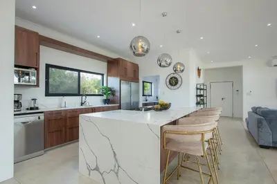 a kitchen with a large white island with bar stools at Giraffe Oasis - Kruger Luxury Family Villa in Marloth Park