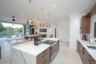 a large kitchen with white counter tops and a table at Giraffe Oasis - Kruger Luxury Family Villa in Marloth Park