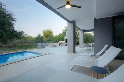 a patio with a white bench and a swimming pool at Giraffe Oasis - Kruger Luxury Family Villa in Marloth Park