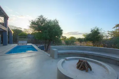 a swimming pool with a fire place next to a swimming pool at Giraffe Oasis - Kruger Luxury Family Villa in Marloth Park