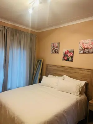 a bed in a bedroom with two paintings on the wall at 9 on Deimos Ave in Polokwane