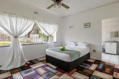 a bedroom with a bed and two windows at Inspire living home in Kempton Park