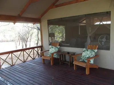 a porch with two chairs and a table on it at Lion Tree Top Lodge in Guernsey Nature Reserve