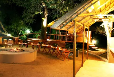 a wooden pavilion with tables and chairs at night at Lion Tree Top Lodge in Guernsey Nature Reserve