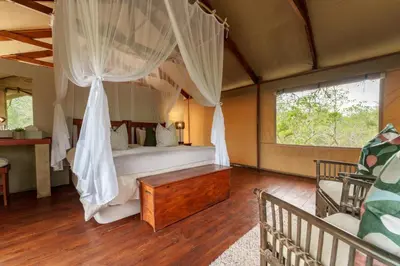 a bedroom with a bed with a mosquito net at Lion Tree Top Lodge in Guernsey Nature Reserve