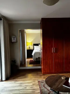 a bedroom with a bed and a large wooden cabinet at Olivestay at Olympus - Apartment in Pretoria