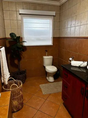a bathroom with a toilet and a window in it at Olivestay at Olympus - Apartment in Pretoria
