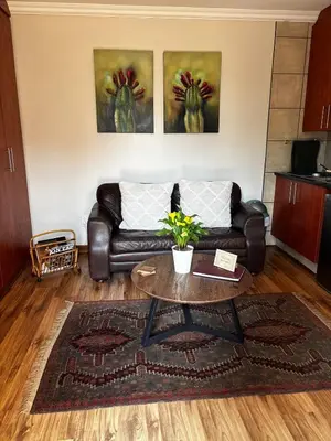 a living room with a leather couch and a table at Olivestay at Olympus - Apartment in Pretoria