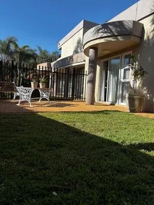 a building with a bench in front of a yard at Olivestay at Olympus - Apartment in Pretoria