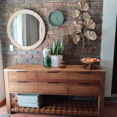 a mirror on a brick wall with a wooden dresser at Melkbos Place in Witbank