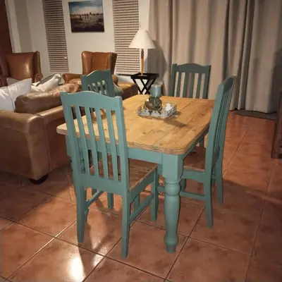 a wooden table with four chairs and a couch at Melkbos Place in Witbank