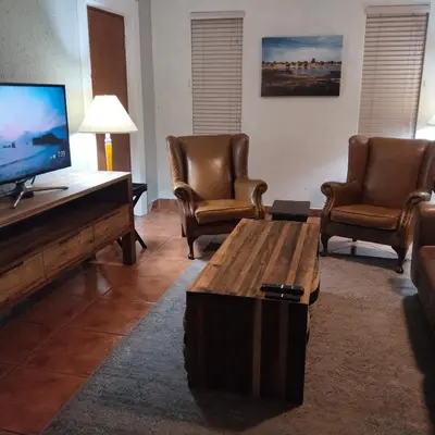 a living room with chairs and a flat screen tv at Melkbos Place in Witbank