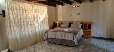 a bedroom with a bed and a large window at Tranquil, Home Away from Home in Pretoria