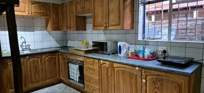 a kitchen with wooden cabinets and a counter top at Tranquil, Home Away from Home in Pretoria
