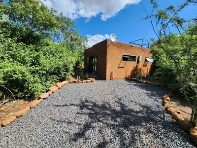a house with a gravel driveway next to a building at Hartbeest Bush Stay #28 in Hartbeespoort