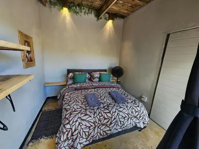 a bedroom with a bed with blue pillows at Hartbeest Bush Stay #28 in Hartbeespoort
