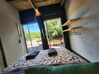 a bedroom with a bed and a large window at Hartbeest Bush Stay #28 in Hartbeespoort