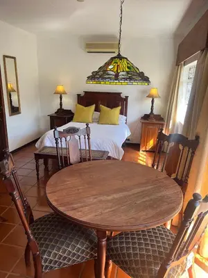a bedroom with a bed and a table and chairs at Sunset magic in Pretoria