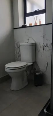 a white toilet in a bathroom with a window at Munyaka in Midrand