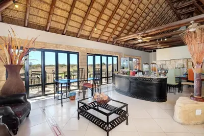 a living room with a bar and tables and chairs at Zebula Golf Estate & Spa Executive Holiday Homes in Mabula