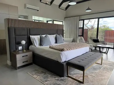 a bedroom with a large bed with a bench in it at blydebushvilla in Hoedspruit