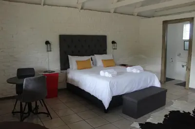 a bedroom with a large bed and a desk and chair at Aurora Village in Polokwane