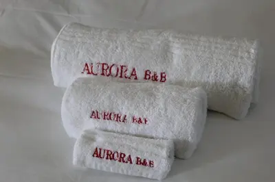 three towels with red writing on them on a bed at Aurora Village in Polokwane