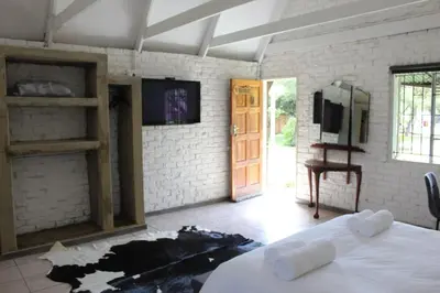 a room with a bed and a tv and a door at Aurora Village in Polokwane