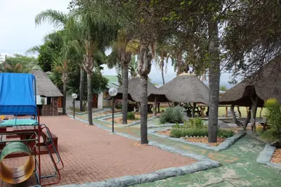 a brick walkway with trees and straw umbrellas at Aurora Village in Polokwane