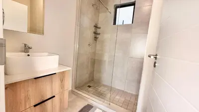 a white bathroom with a shower and a sink at HeartWood Haven in Midrand
