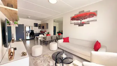 a living room with a white couch and a red tree painting at HeartWood Haven in Midrand