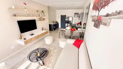 a living room with a white couch and a television at HeartWood Haven in Midrand