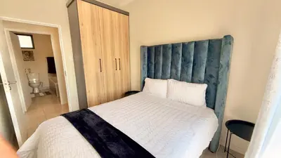 a bedroom with a large bed with a blue headboard at HeartWood Haven in Midrand