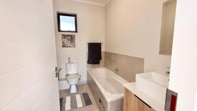 a bathroom with a toilet and a tub and a sink at HeartWood Haven in Midrand