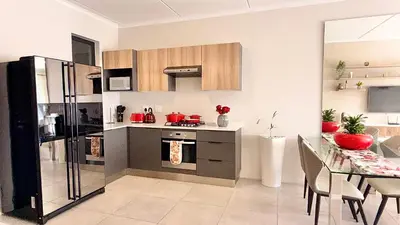 a kitchen with a refrigerator and a table with chairs at HeartWood Haven in Midrand
