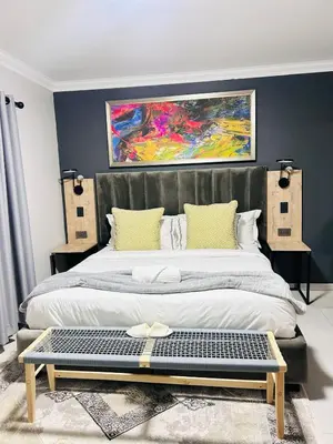 a bedroom with a large bed with a painting on the wall at Tranquil Acres in Nelspruit