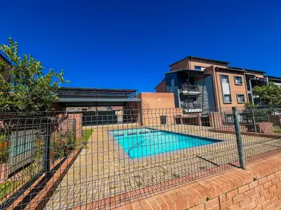 a fence around a swimming pool in front of a building at The Ridge Modern Escape in Midrand