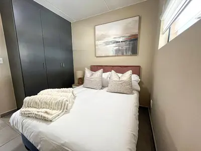 a bedroom with a bed with white sheets and pillows at The Ridge Modern Escape in Midrand