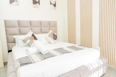 a white bedroom with a large white bed with pillows at Palm Nest in Kempton Park