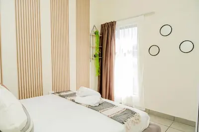 a bedroom with a white bed and a window at Palm Nest in Kempton Park