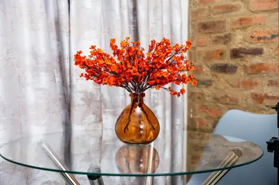 a vase with orange flowers sitting on a glass table at Palm Nest in Kempton Park