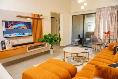 a living room with a couch and a tv and a table at Palm Nest in Kempton Park