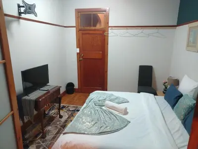 a bedroom with a bed and a television and a door at Brookyard Guest House in Pretoria