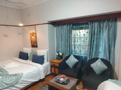 a hotel room with two beds and two chairs at Brookyard Guest House in Pretoria