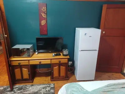 a room with a desk with a refrigerator and a microwave at Brookyard Guest House in Pretoria