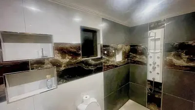 a bathroom with a shower with a toilet paper dispenser at Central Perk Guesthouse in Pretoria