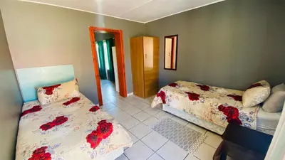 a bedroom with two beds with red flowers on them at Micnels B & B in Pretoria