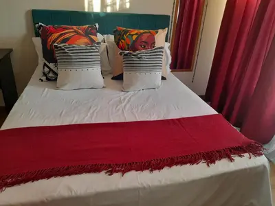 a bed with a red and white blanket and pillows at 2 bedroom family friendly cosy & luxury home, walking distance to Doringkloof Mall in Centurion